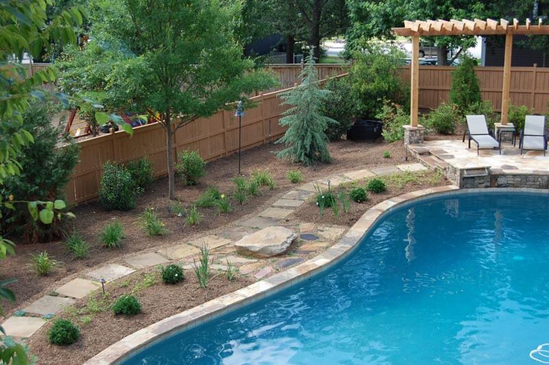 High-end Atlanta pool renovation with stone hardscaping and custom pergola lounge area