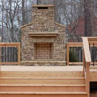 custom deck design with stone outdoor fireplace