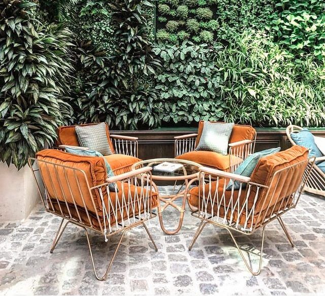 Patio with plush seating area surrounded by greenery