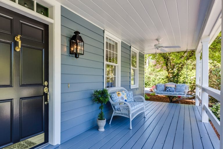 Blue front porch with white trim and and a black front door