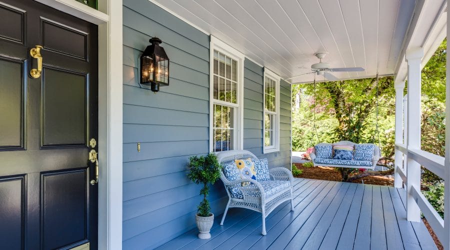 Blue front porch with white trim and and a black front door