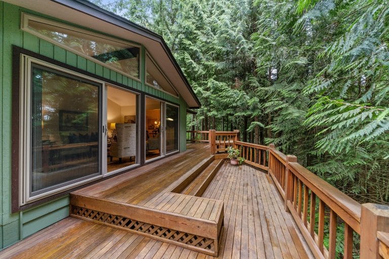 Beautful back deck of a green house with large windows